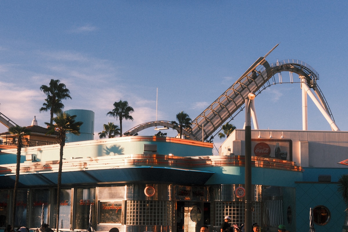 Roller coaster tracks curve over buildings and palm trees at Universal Studios